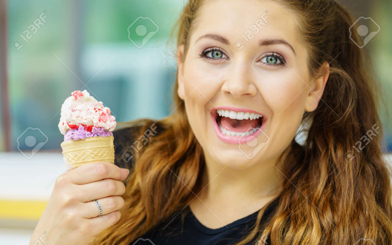 Happy funny young woman with long brown hair eating ice cream having fun. - 133159177 Happy funny young woman with long brown hair eating ice cream having fun. - 133159177
