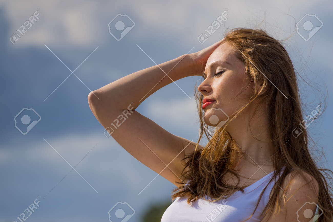 Young woman relaxing outdoor. Female enjoy sunlight against blue sky. - 143016100 Young woman relaxing outdoor. Female enjoy sunlight against blue sky. - 143016100