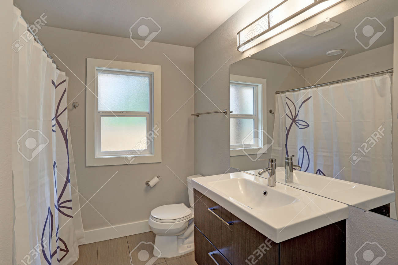 Intérieur De La Salle De Bain Fraîchement Rénové Avec Un Seul Meuble Lavabo Surmonté De Quartz Blanc Sous Un Miroir Sans Cadre Pleine Longueur Monté