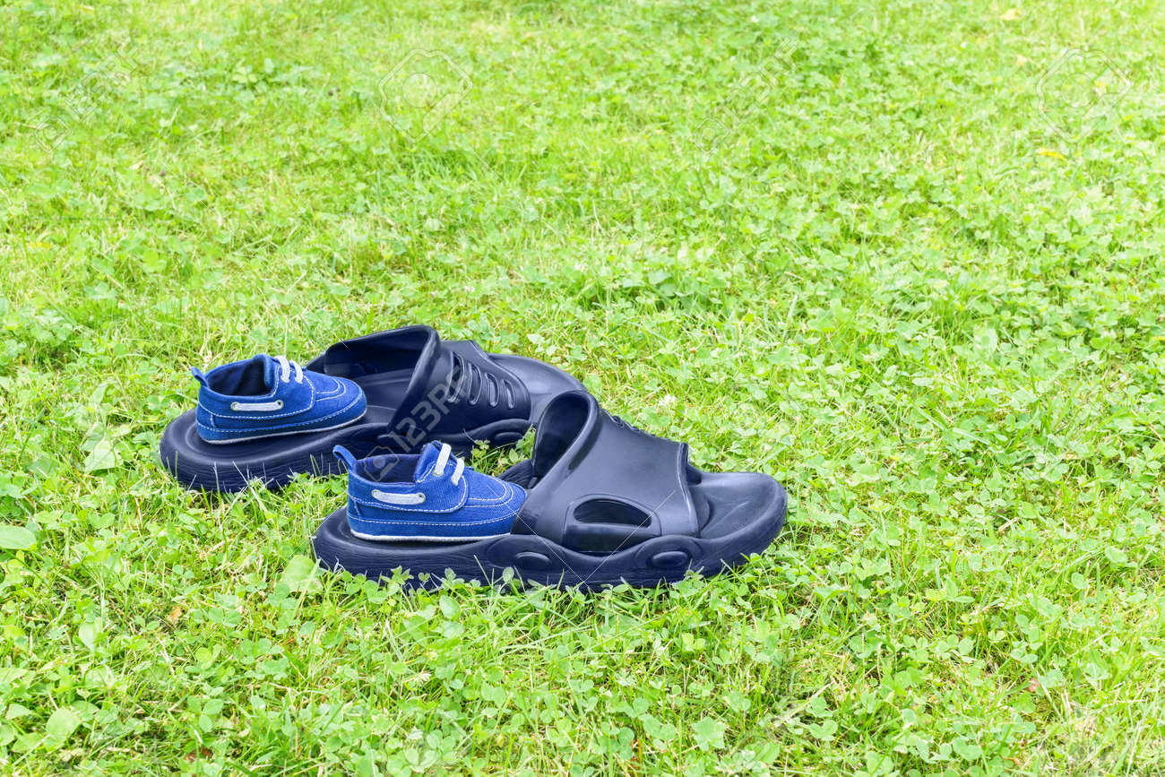 男性のゴム製のスリッパと幼児の靴は芝生の上 します の写真素材 画像素材 Image