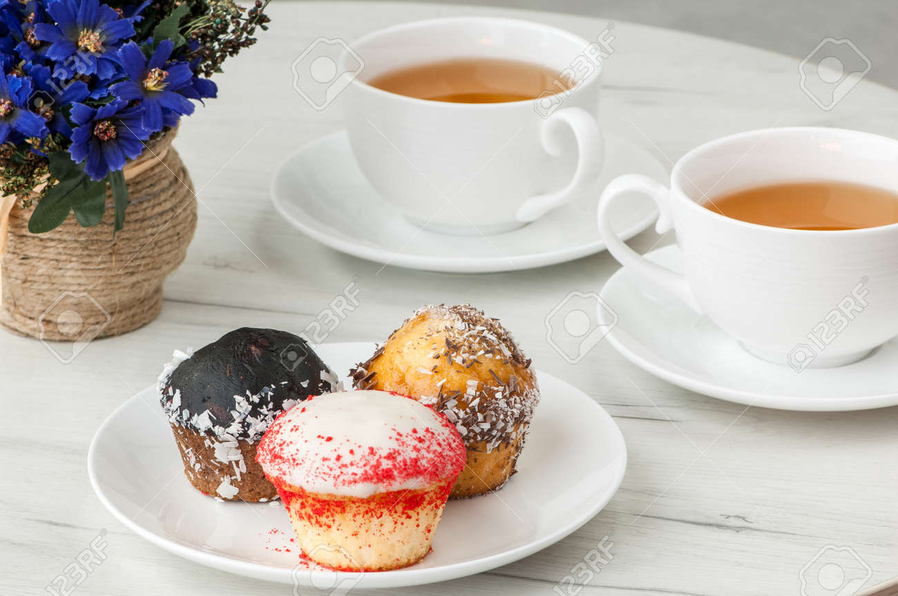cake on a plate and two cups of tea on the table with flowers stock