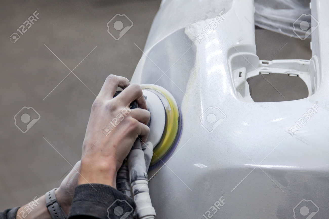 Preparation for painting a car element using sander and putty by a service technician leveling out before applying a primer after damage to a part of the body in an accident in the vehicle workshop - 125825265 Preparation for painting a car element using sander and putty by a service technician leveling out before applying a primer after damage to a part of the body in an accident in the vehicle workshop - 125825265