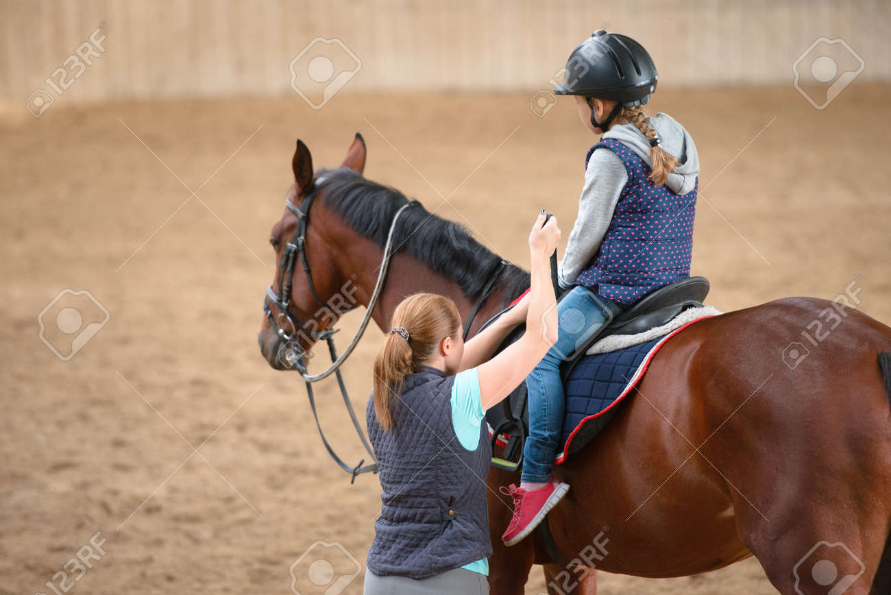 Girl in helmet Learning Horseback Riding. Instructor teaches teen Equestrian. - 74152176 Girl in helmet Learning Horseback Riding. Instructor teaches teen Equestrian. - 74152176
