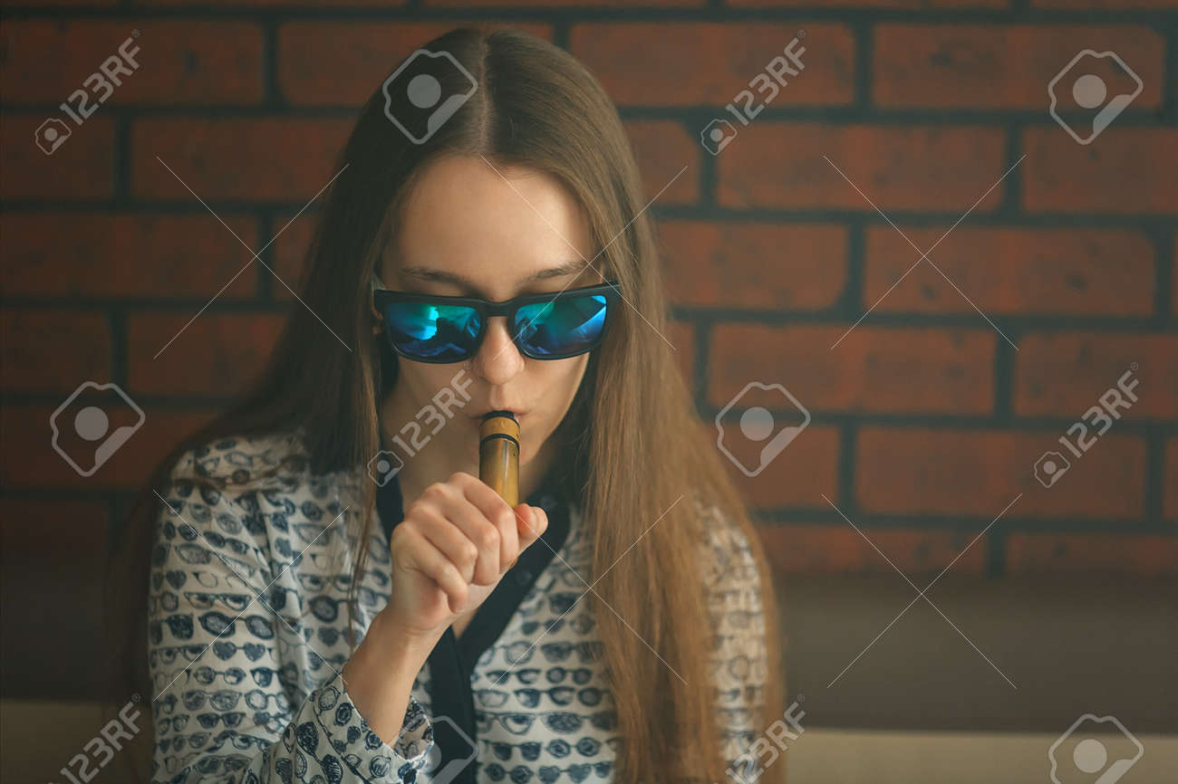 Vape. La belle jeune fille blanche aux lunettes de soleil admet des vapeurs de vapeur à partir de la cigarette électronique. Vaping. Adolescent. Vape. La belle jeune fille blanche aux lunettes de soleil admet des vapeurs de vapeur à partir de la cigarette électronique. Vaping. Adolescent.