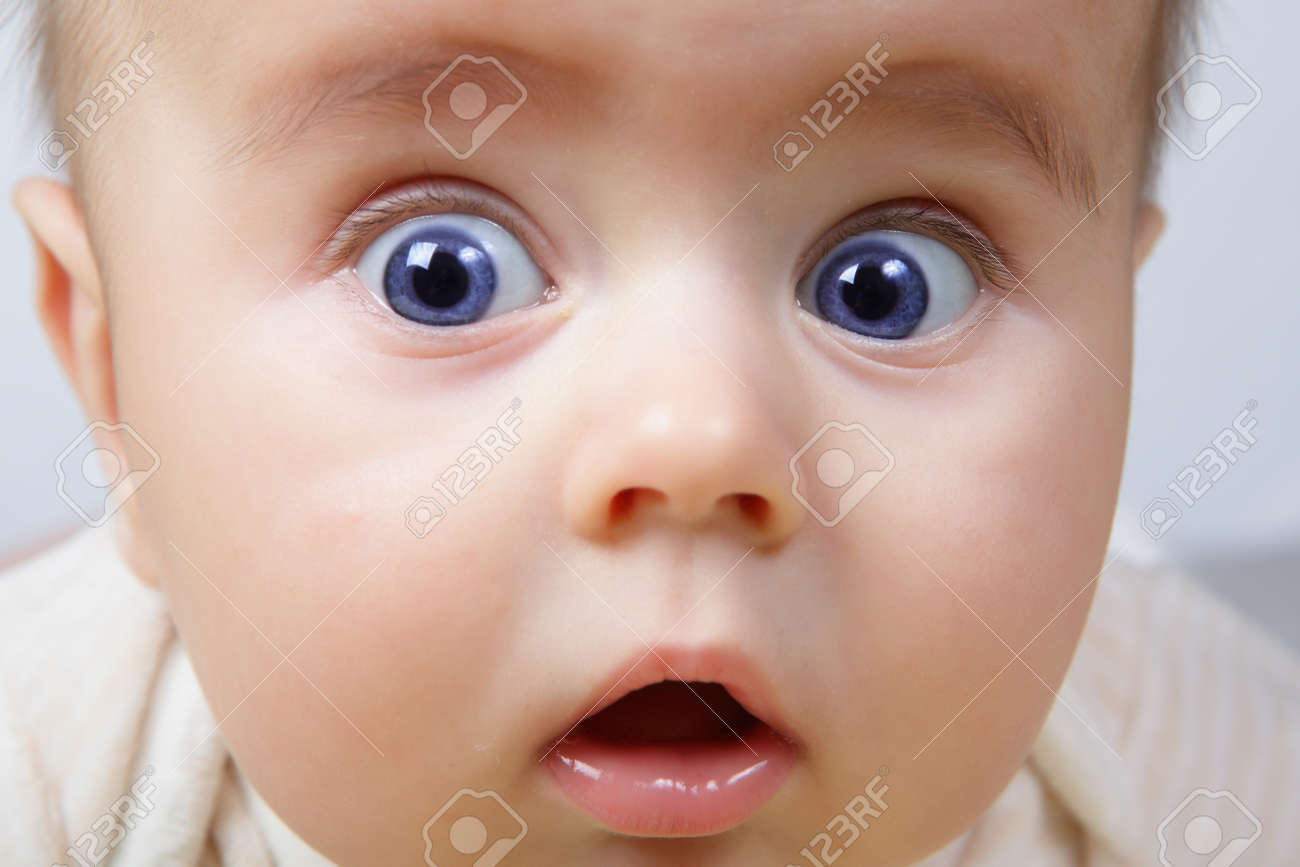 Head Shoot Of Cute Baby With Blue Eyes And Suprise Look Stock Photo