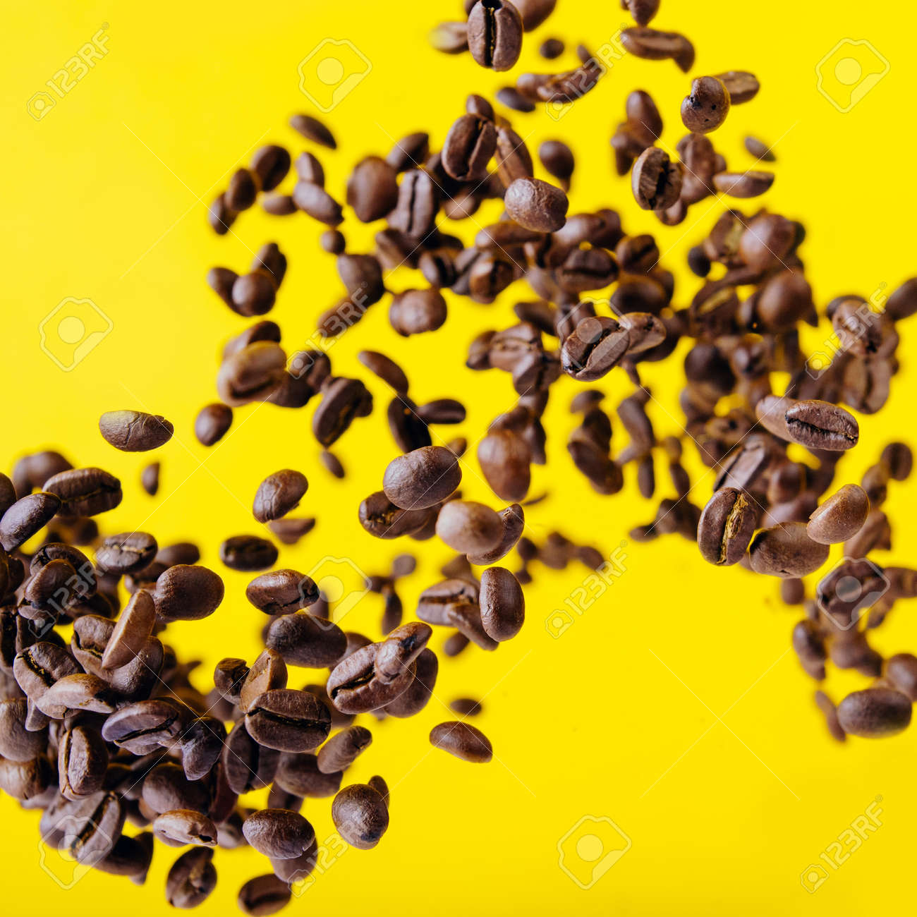 Flying coffee beans on a bright yellow background - 151355188 Flying coffee beans on a bright yellow background - 151355188
