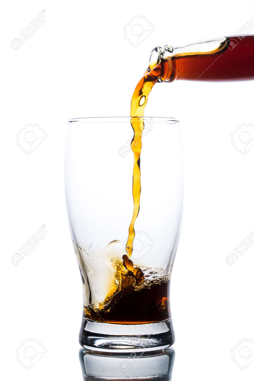 Brown ale pours from a bottle into a glass on a light background - 152811752 Brown ale pours from a bottle into a glass on a light background - 152811752