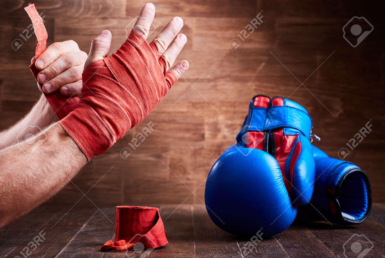 木の板に包帯や手袋をボクシングの彼の手を包む陽気な男 の写真素材 画像素材 Image