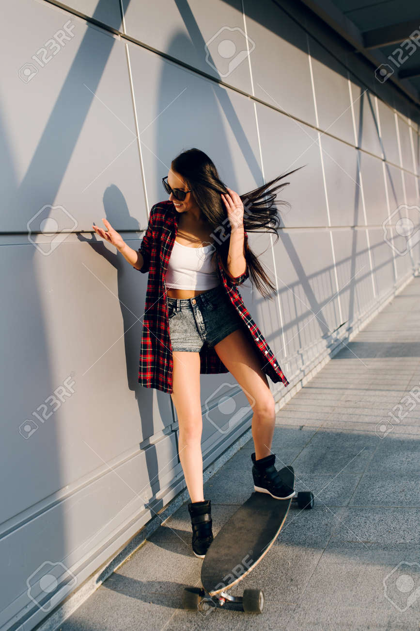 Pretty young fashion sexy swag girl riding wooden longboard on..