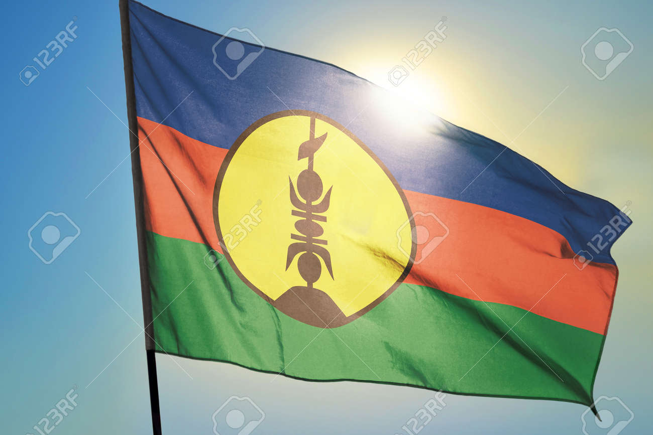 New Caledonia flag waving on the wind in front of sun - 166480119 New Caledonia flag waving on the wind in front of sun - 166480119