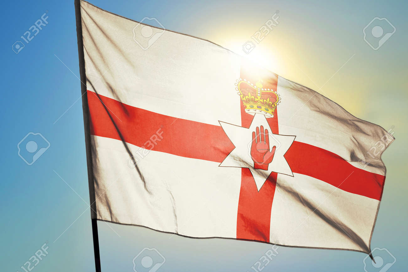 Northern Ireland flag waving on the wind in front of sun - 166480124 Northern Ireland flag waving on the wind in front of sun - 166480124