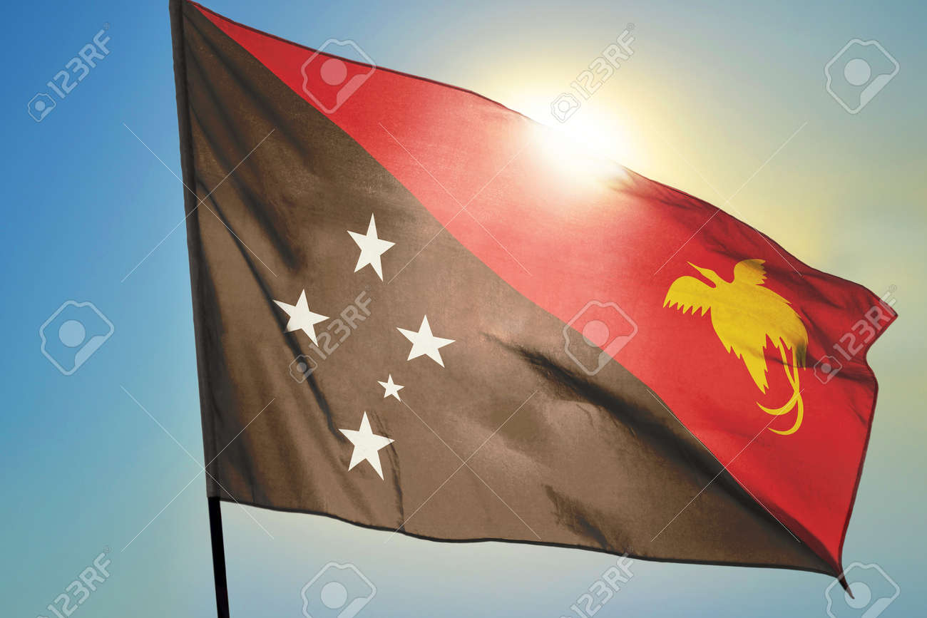 Papua New Guinea flag waving on the wind in front of sun - 166480128 Papua New Guinea flag waving on the wind in front of sun - 166480128