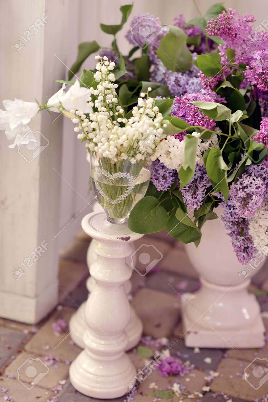 On The Floor Are Large White Vases With Bouquets Of Lilac And