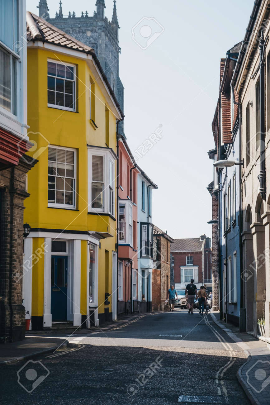 Cromer, Regno Unito - 20 aprile 2019: Persone che camminano davanti a case colorate a Cromer, una cittadina balneare nel Norfolk e una popolare destinazione per le vacanze in famiglia nel Regno Unito. - 124584880