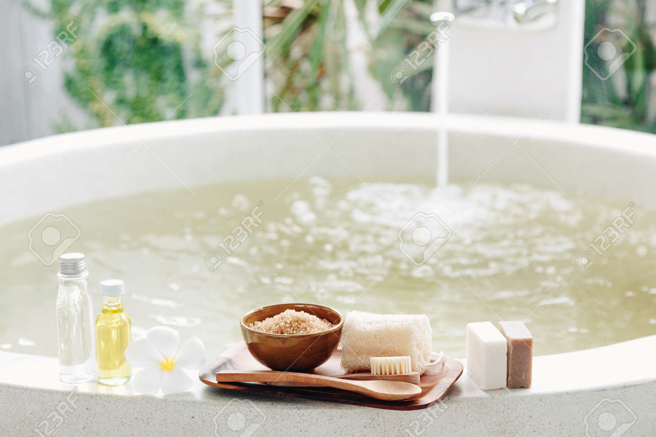 Spa decoration, natural organic products on a bathtube. Loofah, towel and frangipani flower - 54740902 Spa decoration, natural organic products on a bathtube. Loofah, towel and frangipani flower - 54740902