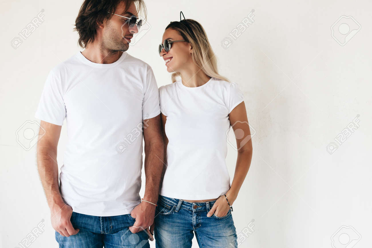 Two hipster models man and woman wearing blanc t-shirt, jeans and sunglasses posing against white wall, toned photo, front tshirt mockup for couple - 63235766 Two hipster models man and woman wearing blanc t-shirt, jeans and sunglasses posing against white wall, toned photo, front tshirt mockup for couple - 63235766