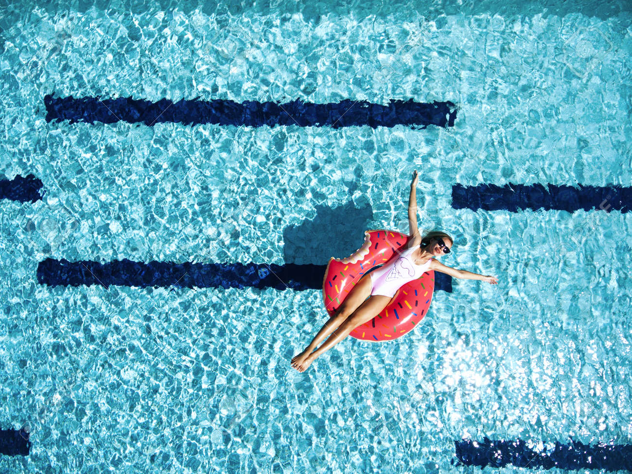 Woman relaxing on donut lilo in the pool water in hot sunny day. Summer holiday idyllic. Top view. - 69179293 Woman relaxing on donut lilo in the pool water in hot sunny day. Summer holiday idyllic. Top view. - 69179293