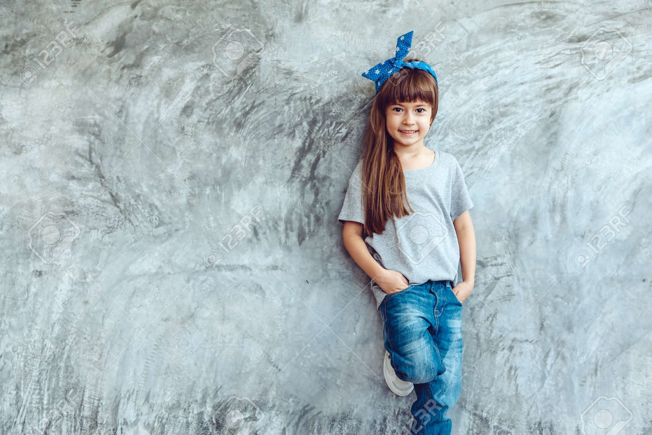 空の灰色の T シャツとジーンズの大まかな Concgrete 壁 シンプルなストリート ファッションにポーズを着てファッション子供キッズ スタイル の写真素材 画像素材 Image