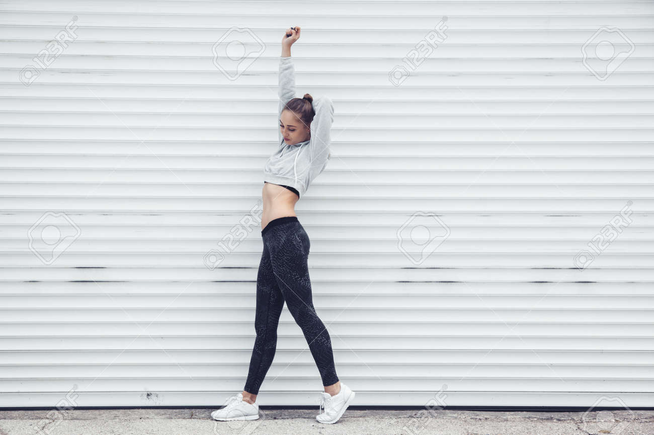Fitness sporty girl wearing fashion sportswear over street wall,..