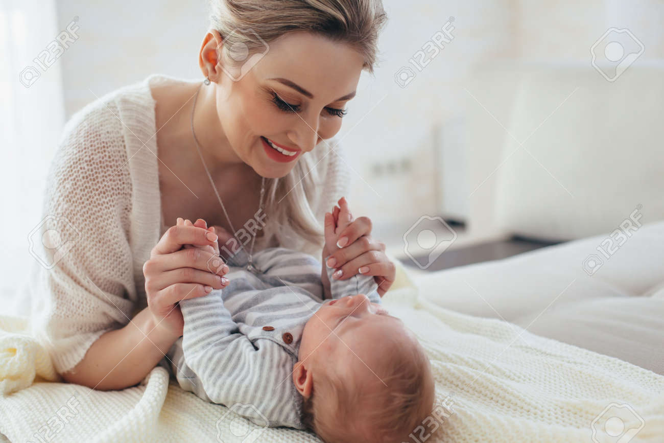 ベッドの上にお母さんと一緒に生後2ヶ月の赤ちゃんの家の肖像画 子供と遊んでいる母親 の写真素材 画像素材 Image