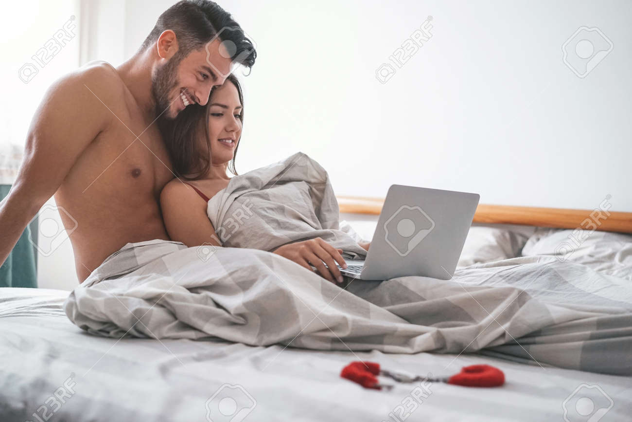 Happy Couple Watching On Computer While Lying On Bed Under Blanket - Young  Lover Watching Role Games Sex Video On Laptop - People, Sexual, Intimate,  Youth And Technology Concept Stock Photo, Picture