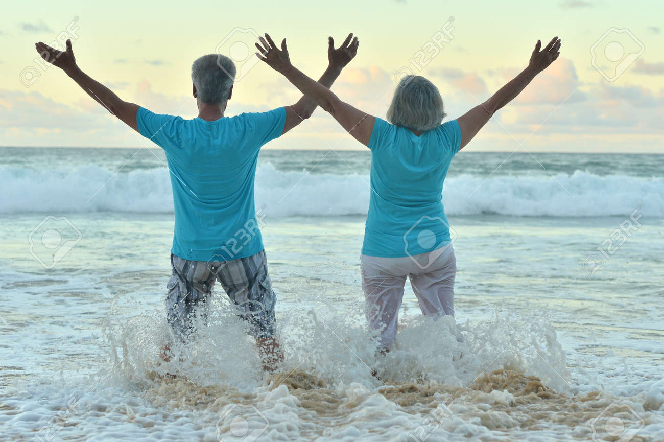 Beautiful happy elderly couple rest at tropical resort with hands up - 50745770 Beautiful happy elderly couple rest at tropical resort with hands up - 50745770