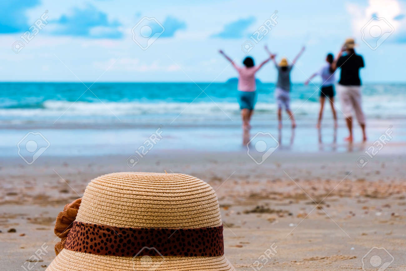 hat and group of happy young people relaxation at the beach on