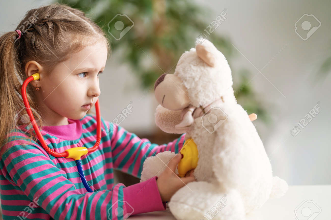 Attentive adorable small girl wearing in everyday clothes, using stethoscope on teddy bear. Attractive little preschooler playing doctor patient game in clinic, children healthcare concept. Treatment. - 145987813 Attentive adorable small girl wearing in everyday clothes, using stethoscope on teddy bear. Attractive little preschooler playing doctor patient game in clinic, children healthcare concept. Treatment. - 145987813