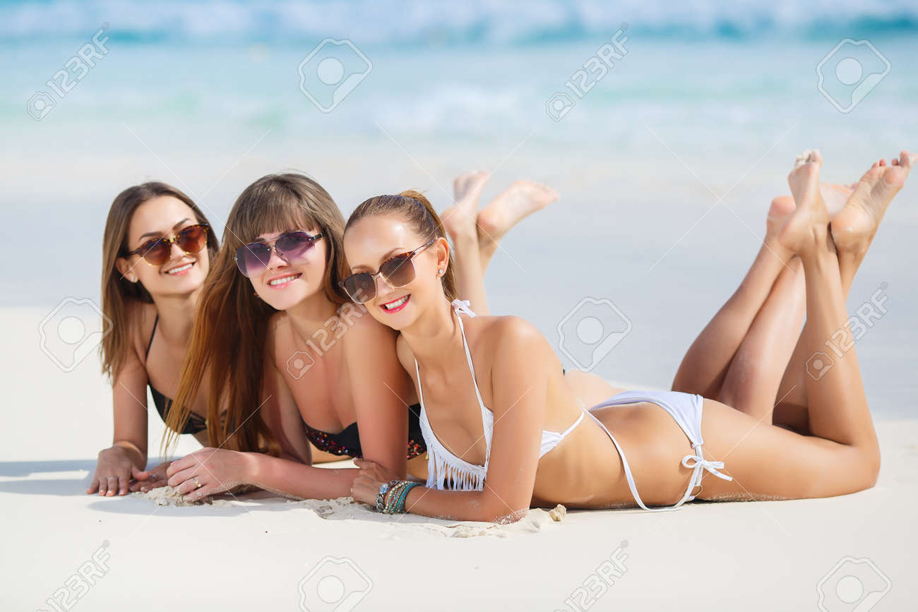 three slim young girls in bikinis on the beach summer holidays