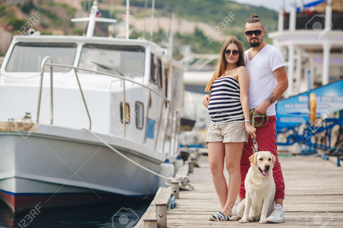 犬とのカップルします 妊娠中の女性は 彼女の夫とその犬ゴールデン レトリーバー 若いカップルは 海で犬を連れて歩いてください 幸せな家族の概念 の写真素材 画像素材 Image