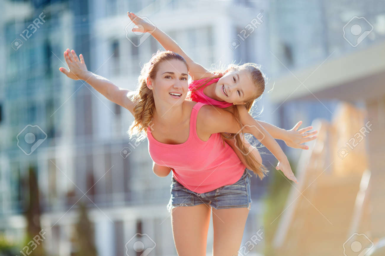 Happy mother giving her son a piggyback ride in the city stock photo