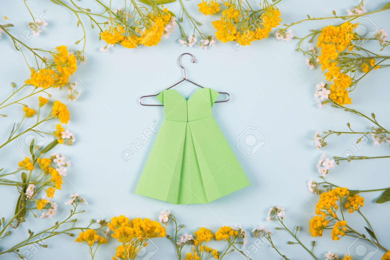 Green Paper Origami Dress On Hanger Surrounded With Yellow And