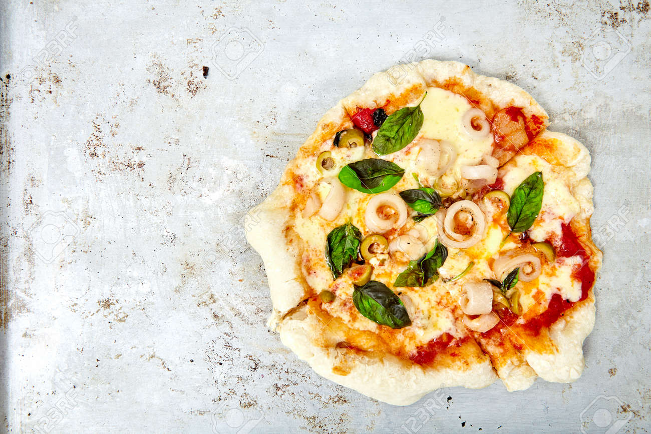 top view shot of homemade pizza made of fresh basil squid stripes