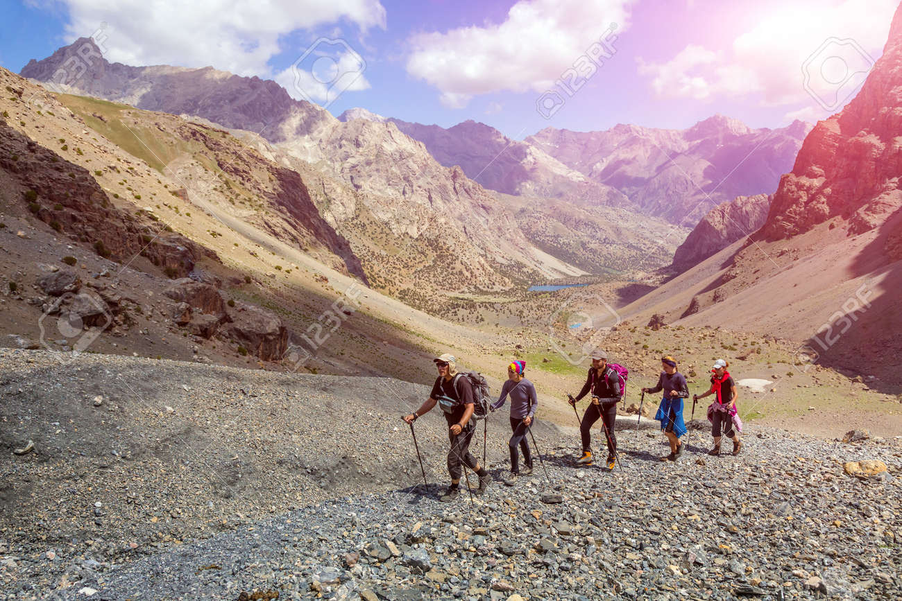 People walking along rocky footpath positive faces trekking gear poles sporty clothing bright panorama blue sky sunny day background - 52722337 People walking along rocky footpath positive faces trekking gear poles sporty clothing bright panorama blue sky sunny day background - 52722337