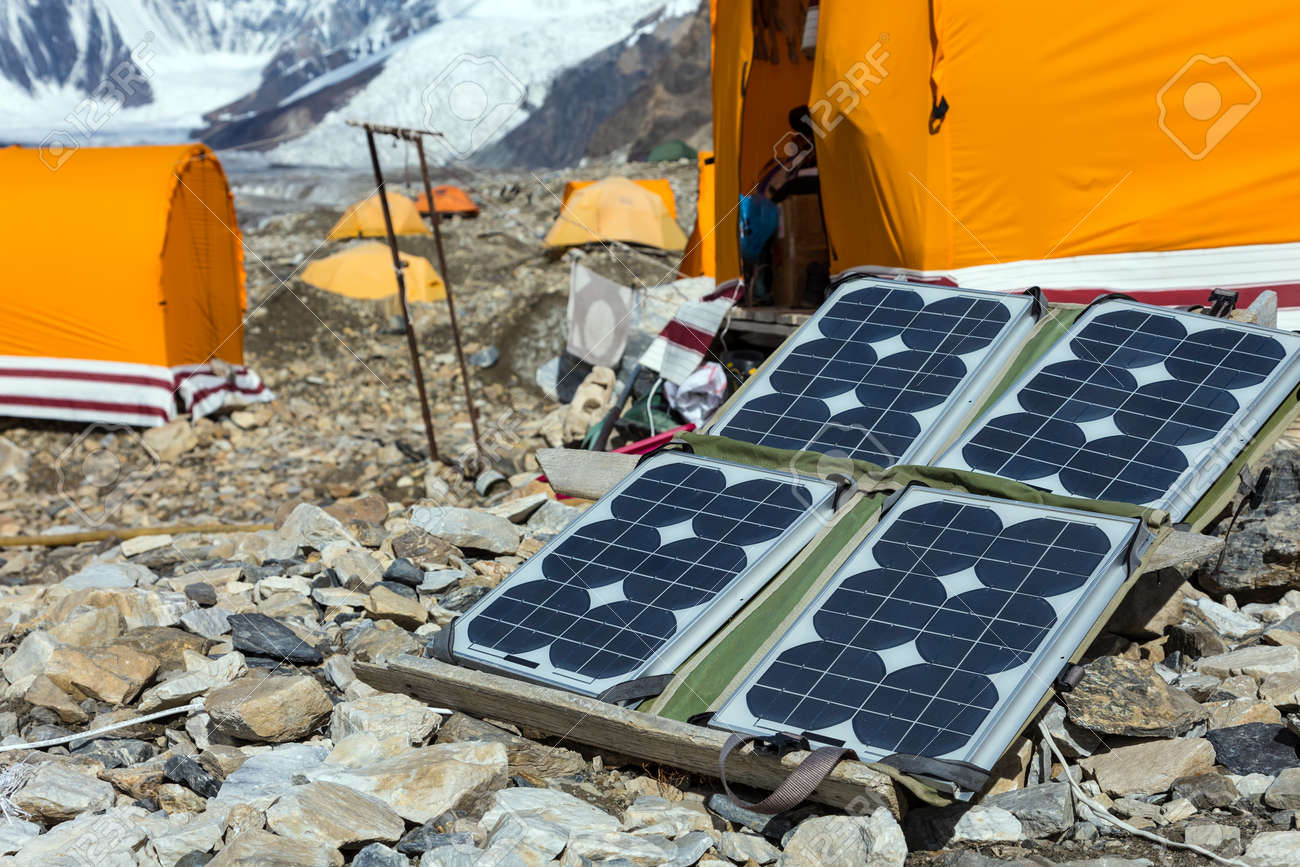 Solar Battery on Rocky Glacier Moraine for Electricity Supply of Sport Mountain Expedition in Wilderness Country with Camping Tents on Background - 56954648 Solar Battery on Rocky Glacier Moraine for Electricity Supply of Sport Mountain Expedition in Wilderness Country with Camping Tents on Background - 56954648