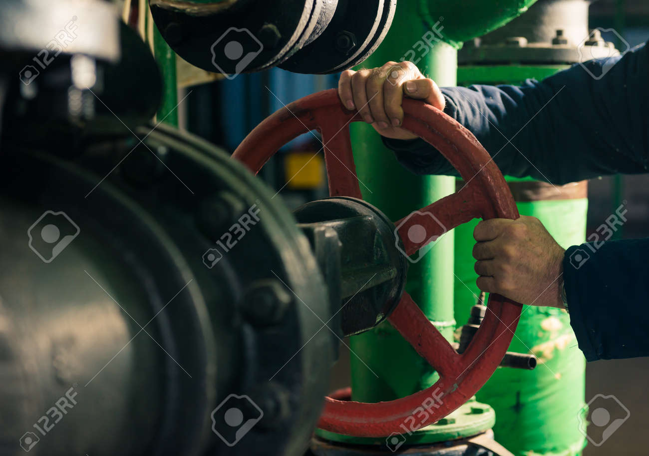 man holding red valves in technical room - 116678585 man holding red valves in technical room - 116678585