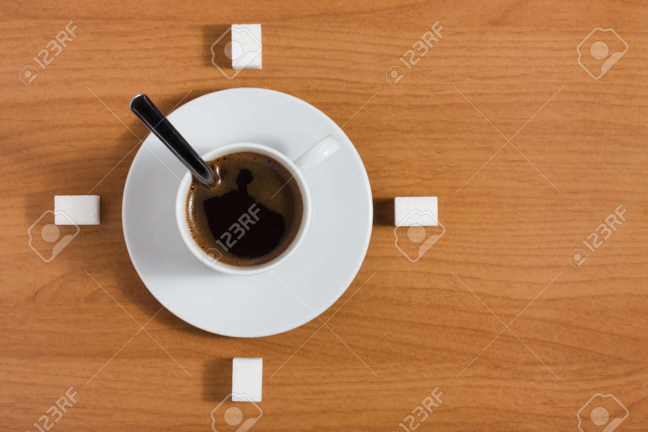 White coffee cup with saucer and sugar like a clock on a wooden brown table, top view - 15794613 White coffee cup with saucer and sugar like a clock on a wooden brown table, top view - 15794613
