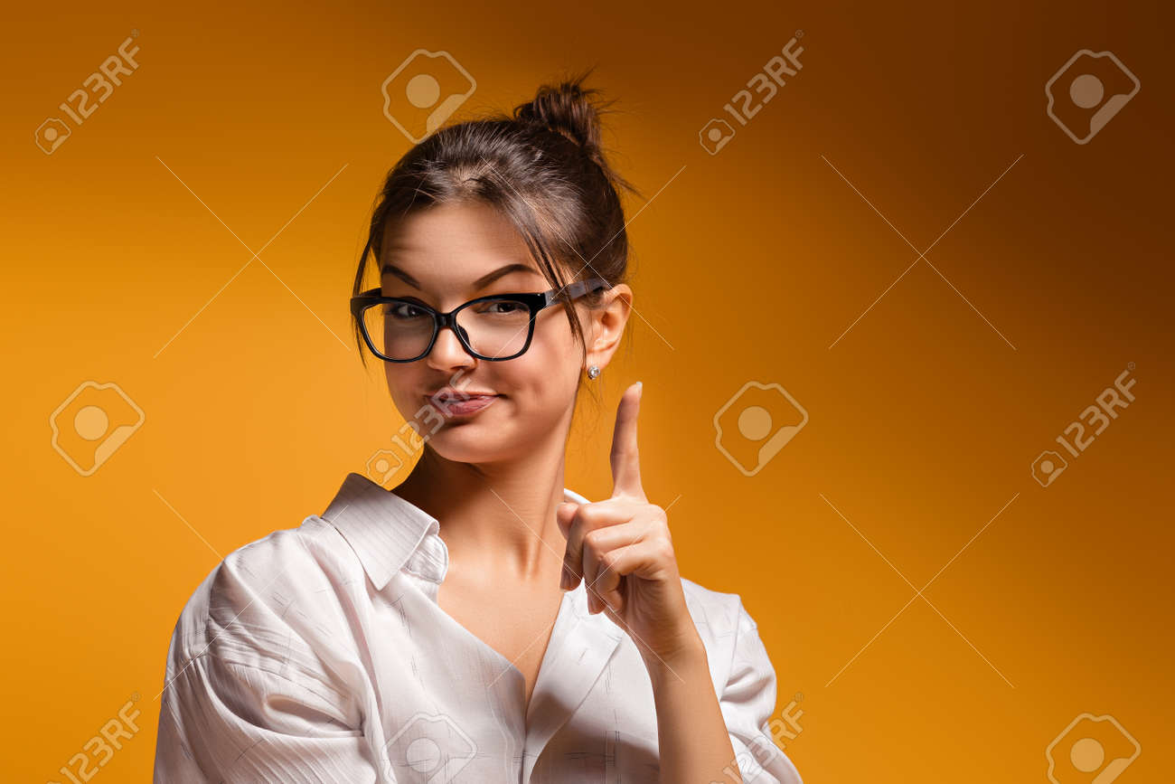 眼鏡 黄色の背景穏やかな夢を見ている若い女の子と思った女性の思いやりのある女の子アイデア来た女の子の頭 女性の中でポーズの女の子を人差し指に発生します の写真素材 画像素材 Image