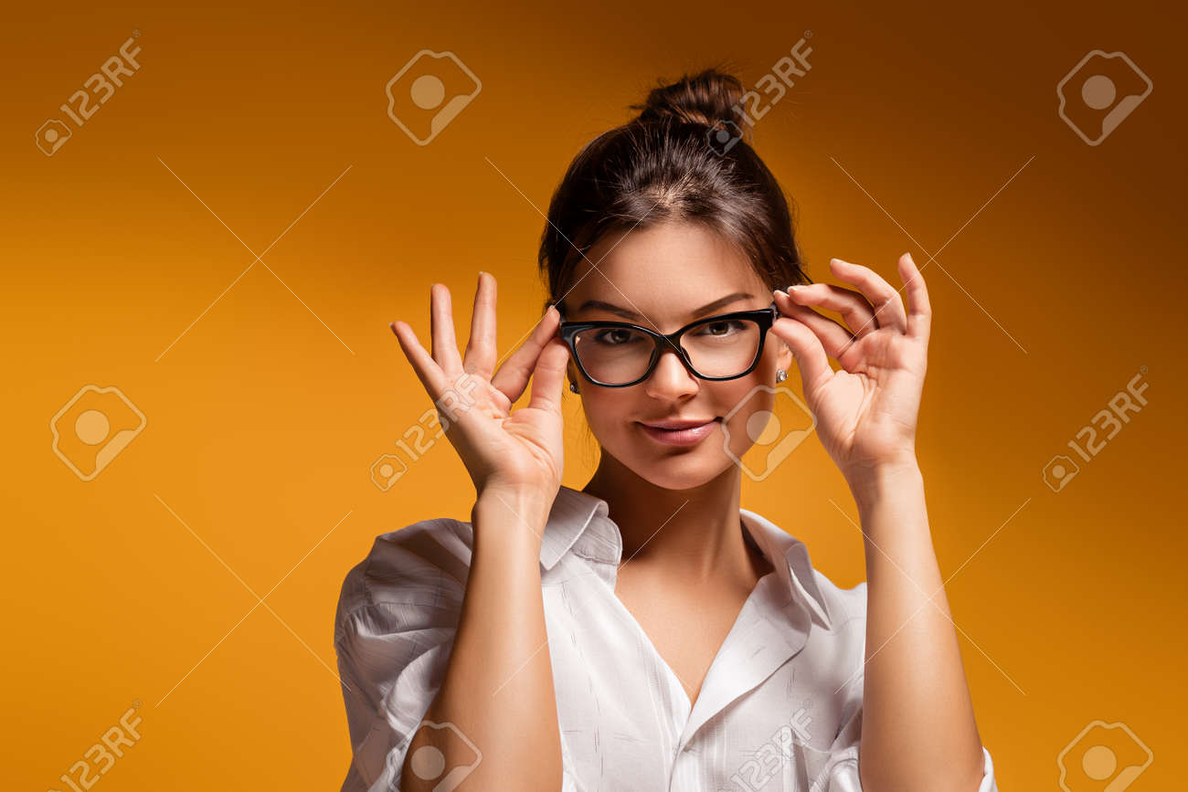 若い可愛い黄色の背景優しい夢を見て若い女の子と思った女性のポーズのメガネで感情的な美少女です 思いやりのある女の子 思いやりのある女性 女の子はメガネ女を調整します の写真素材 画像素材 Image