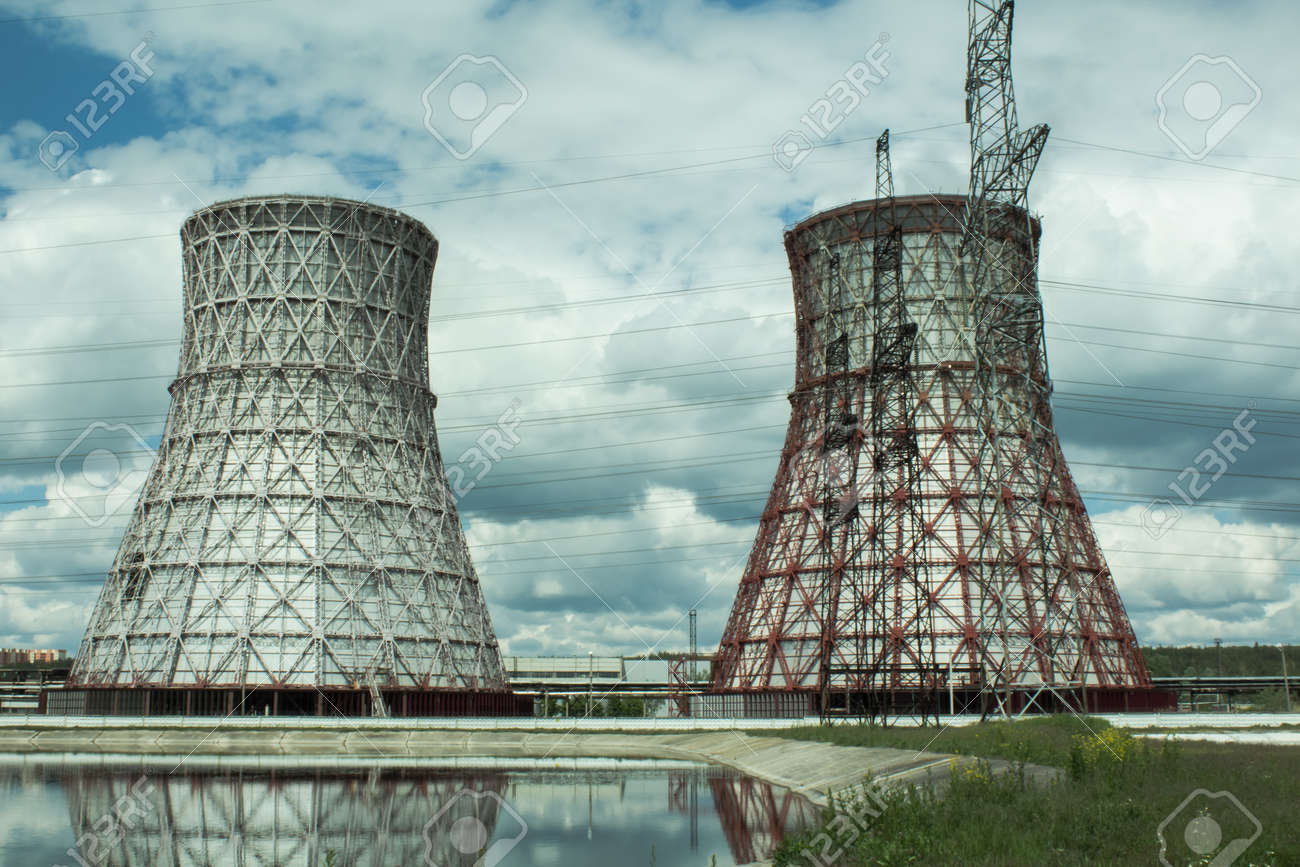View of the power plant and cooling towers. The smoke goes out from a cooling tower of an operating power station. Cooling towers of a thermoelectric power station are reflected in a technical reservoir. Concept of ecology, environmental protection. - 148540441 View of the power plant and cooling towers. The smoke goes out from a cooling tower of an operating power station. Cooling towers of a thermoelectric power station are reflected in a technical reservoir. Concept of ecology, environmental protection. - 148540441