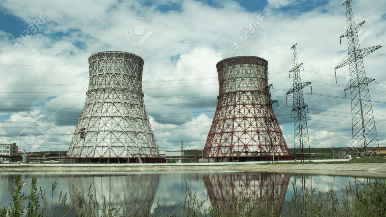 View of the power plant and cooling towers. The smoke goes out from a cooling tower of an operating power station. Cooling towers of a thermoelectric power station are reflected in a technical reservoir. Concept of ecology, environmental protection. - 148546725 View of the power plant and cooling towers. The smoke goes out from a cooling tower of an operating power station. Cooling towers of a thermoelectric power station are reflected in a technical reservoir. Concept of ecology, environmental protection. - 148546725