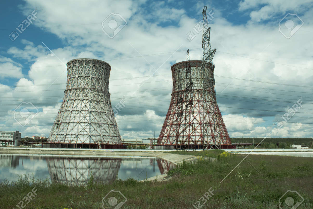 View of the power plant and cooling towers. The smoke goes out from a cooling tower of an operating power station. Cooling towers of a thermoelectric power station are reflected in a technical reservoir. Concept of ecology, environmental protection. - 148550826 View of the power plant and cooling towers. The smoke goes out from a cooling tower of an operating power station. Cooling towers of a thermoelectric power station are reflected in a technical reservoir. Concept of ecology, environmental protection. - 148550826