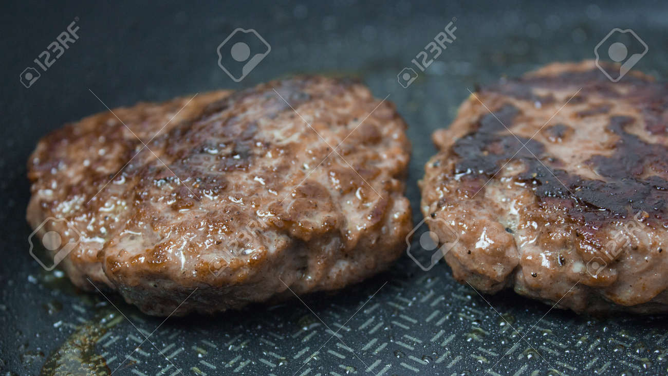 The chef puts beef patties into a frying pan. Juicy beef cutlet is fried in a pan. - 152885130 The chef puts beef patties into a frying pan. Juicy beef cutlet is fried in a pan. - 152885130