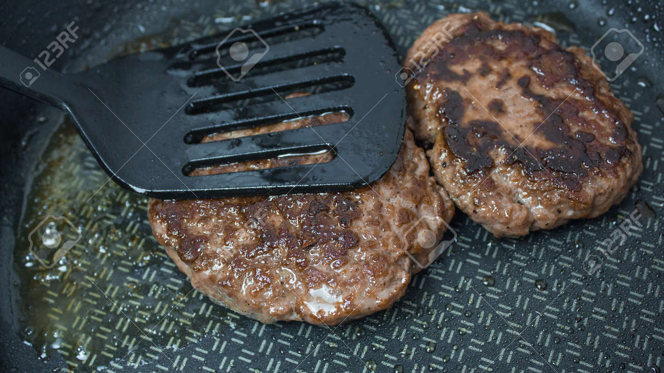 The chef puts beef patties into a frying pan. Juicy beef cutlet is fried in a pan. - 152885507 The chef puts beef patties into a frying pan. Juicy beef cutlet is fried in a pan. - 152885507