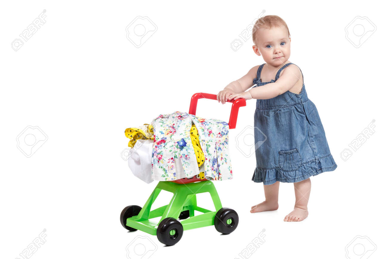 Little girl in denim dress driven child plastic shopping trolley full of clothes isolated on white background - 39951278 Little girl in denim dress driven child plastic shopping trolley full of clothes isolated on white background - 39951278