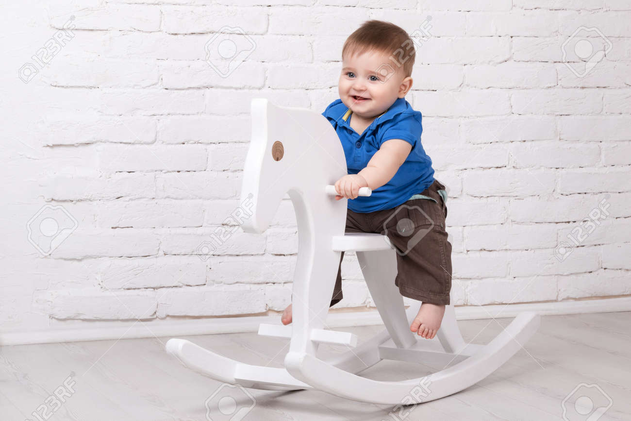 Little smiling baby sitting on a white horse, wooden rocking - 52804015 Little smiling baby sitting on a white horse, wooden rocking - 52804015