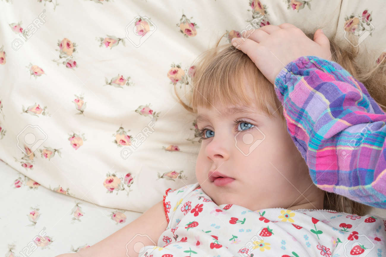 子供の手が頭の上のベッドにある 彼女の病気の妹をなでる の写真素材 画像素材 Image