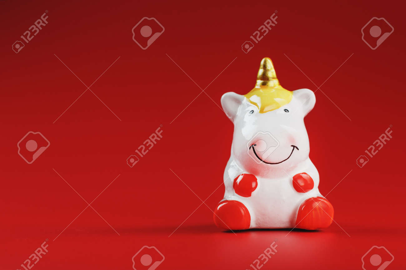 Small figure of a unicorn on a red background. The concept of magic, children's dreams. Free space. - 165524381 Small figure of a unicorn on a red background. The concept of magic, children's dreams. Free space. - 165524381
