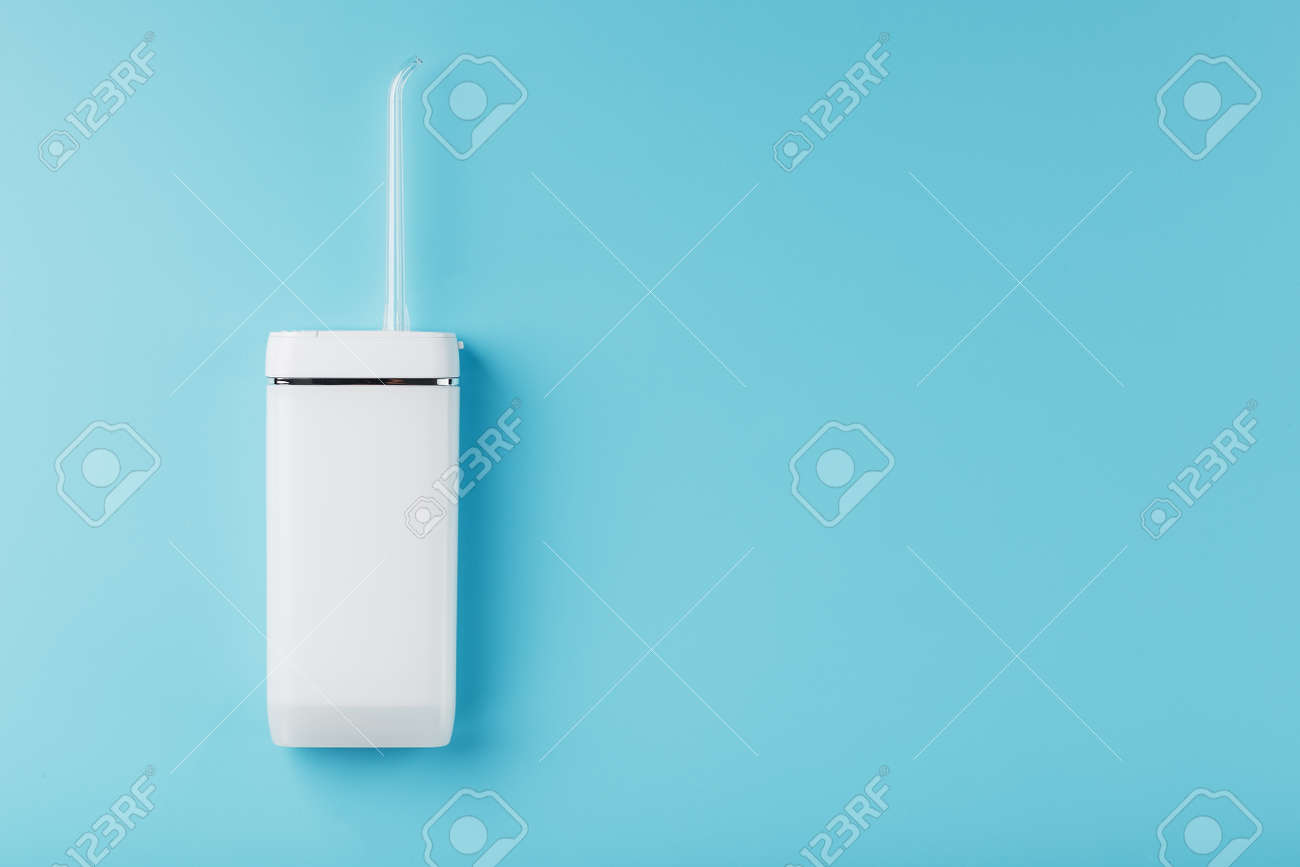 Mobile irrigator for cleaning the oral cavity on a blue background. For brushing your teeth and a snow-white smile. Free space - 169206292 Mobile irrigator for cleaning the oral cavity on a blue background. For brushing your teeth and a snow-white smile. Free space - 169206292