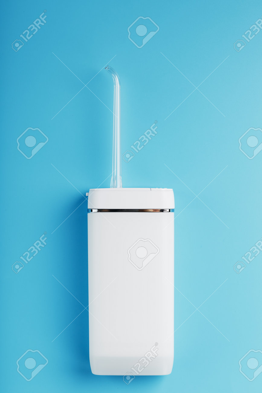 Mobile irrigator for cleaning the oral cavity on a blue background. For brushing your teeth and a snow-white smile. Free space - 169206295 Mobile irrigator for cleaning the oral cavity on a blue background. For brushing your teeth and a snow-white smile. Free space - 169206295